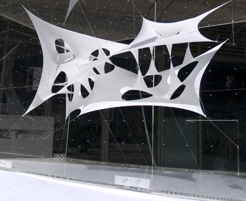 White tensile membrane prototype suspended on cable nets inside a glazed gallery