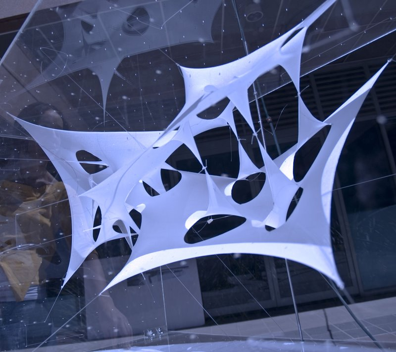 Close view of a white membrane physical model showing tensioned surfaces and open voids